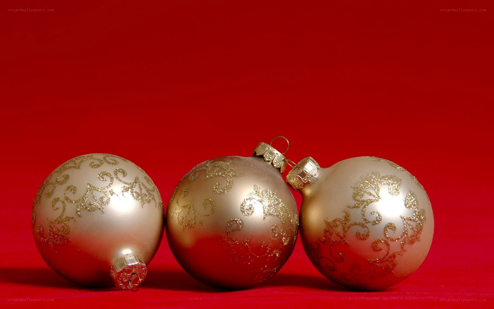 three gold ornaments on red