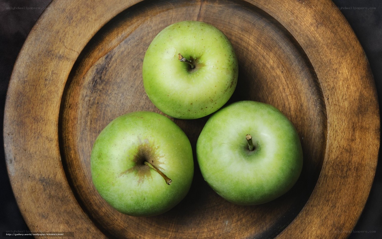 Three green apples on wood
