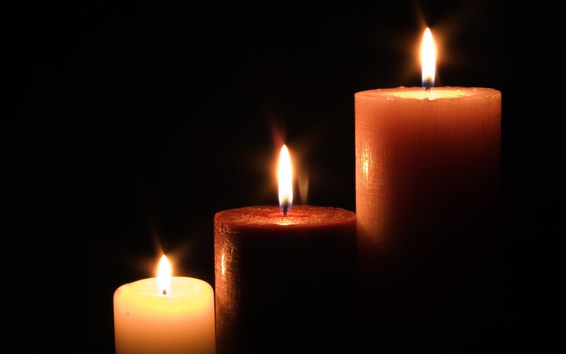 Three lit candles in darkness