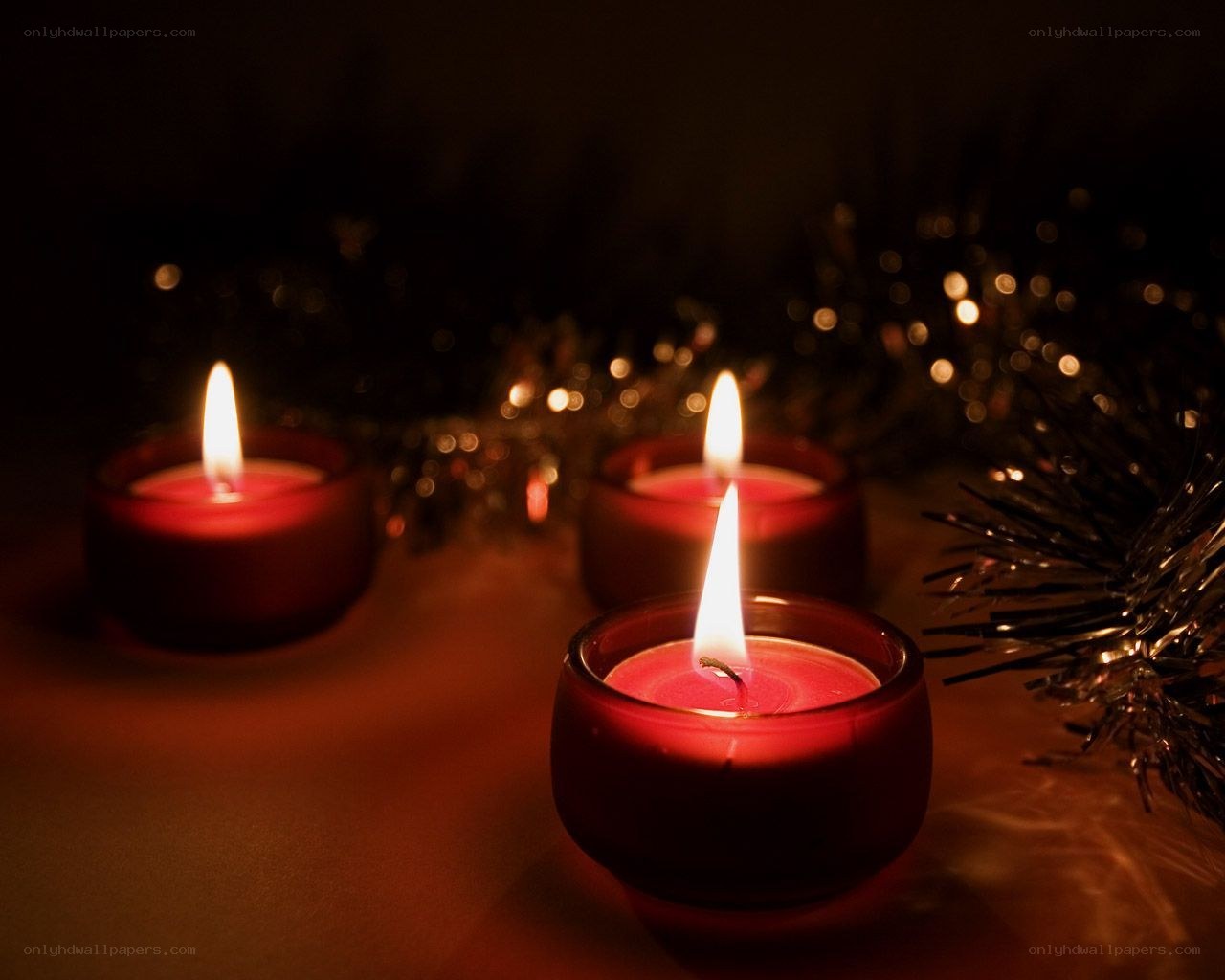 Three lit candles in red holders
