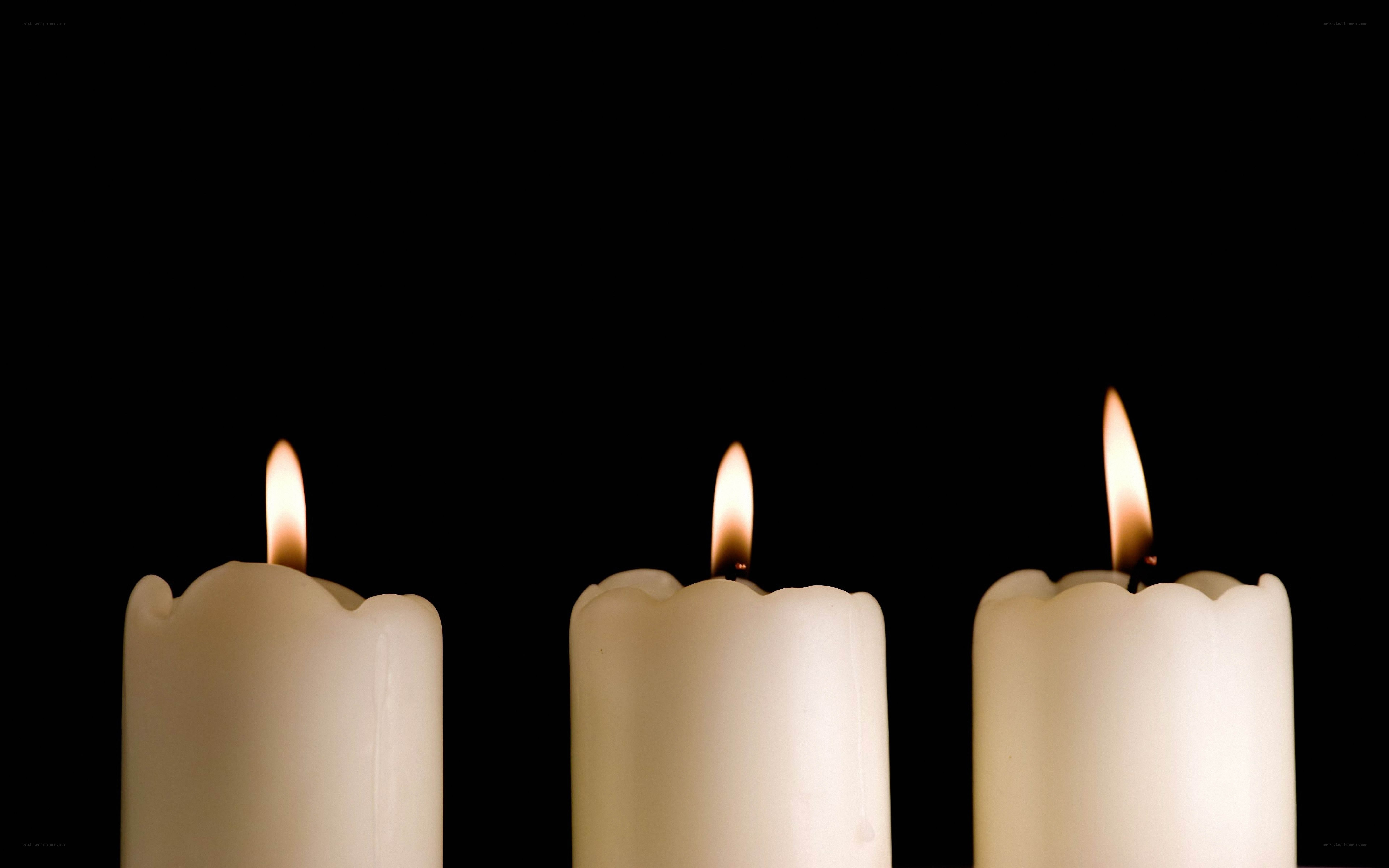 Three lit candles on black