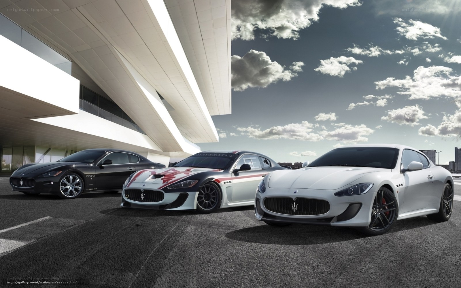 Three Maserati cars in front of building