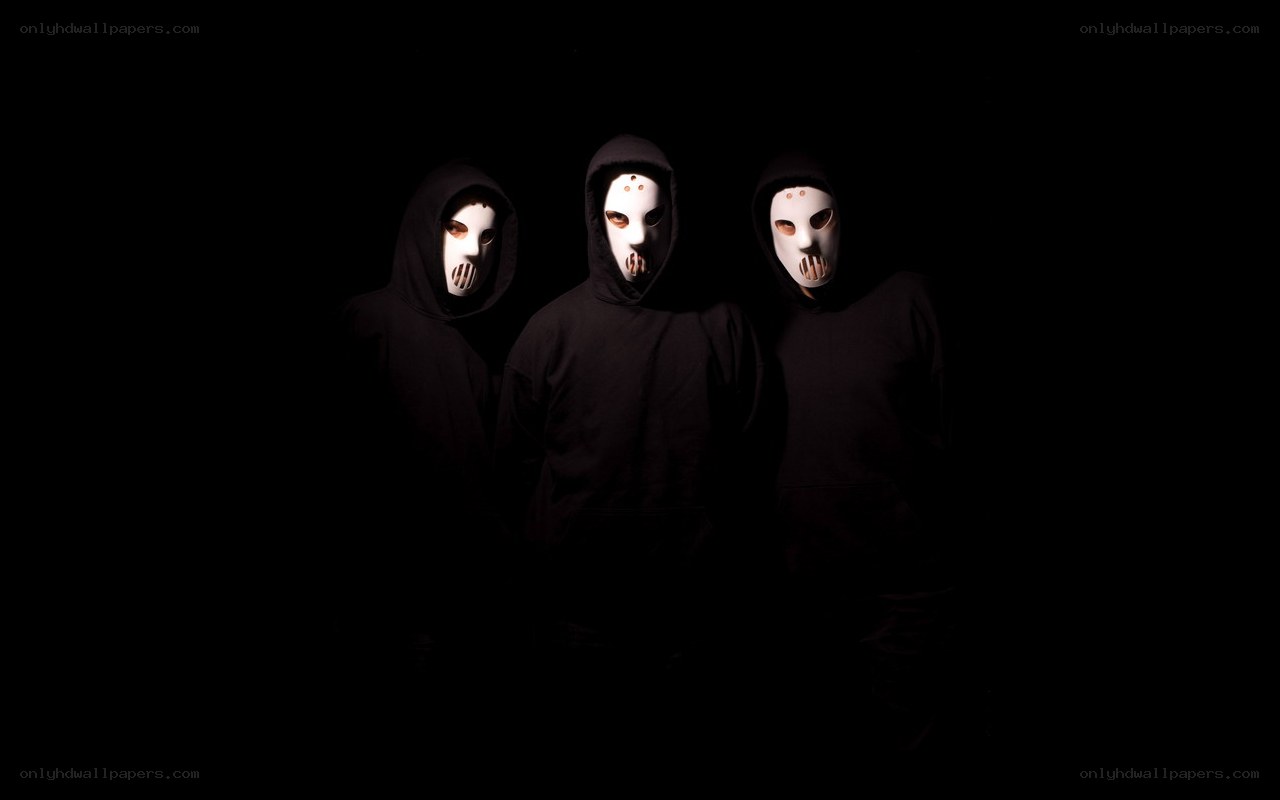 three masked figures in black hoodies