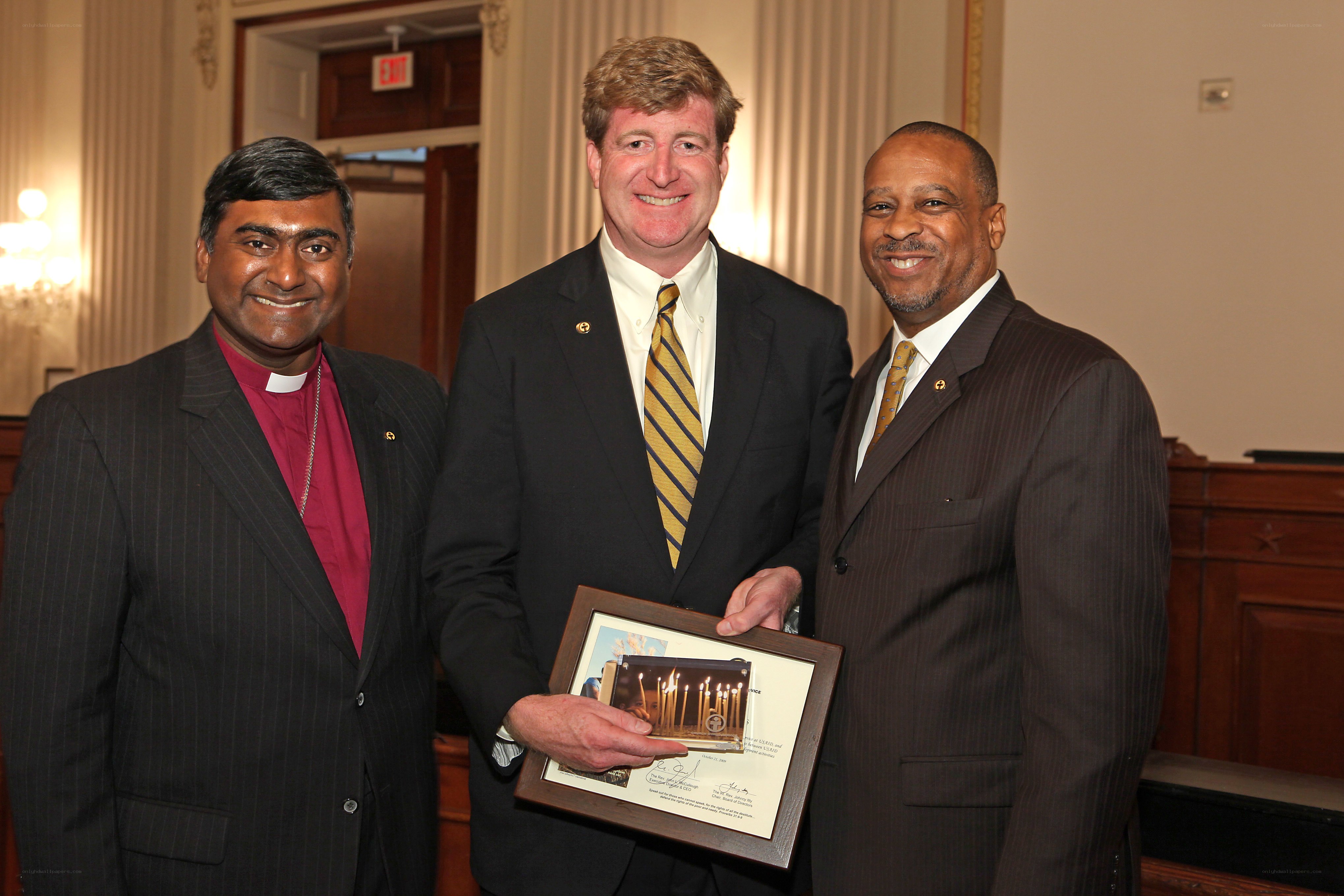 Three men at formal event with plaque