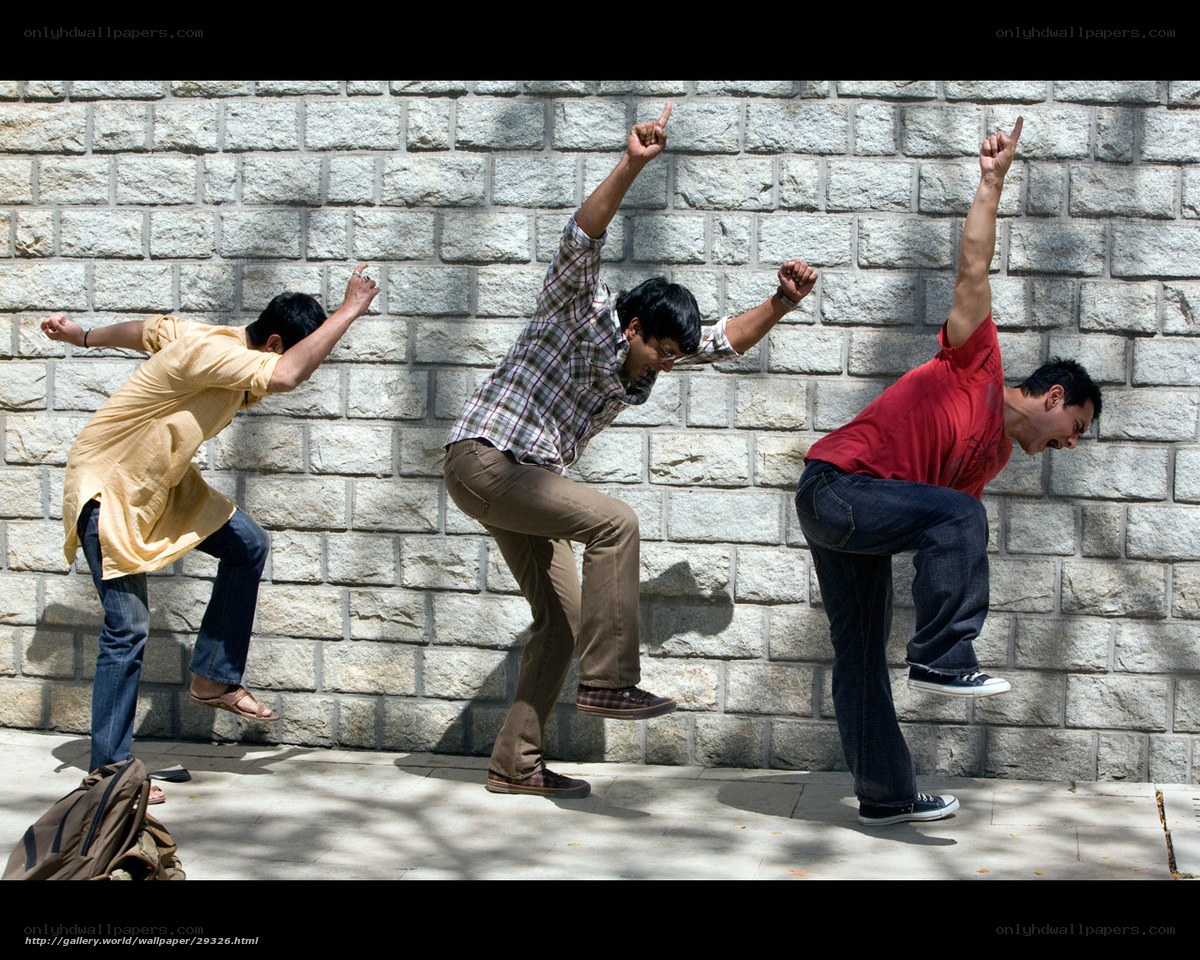 Three men dancing against a wall