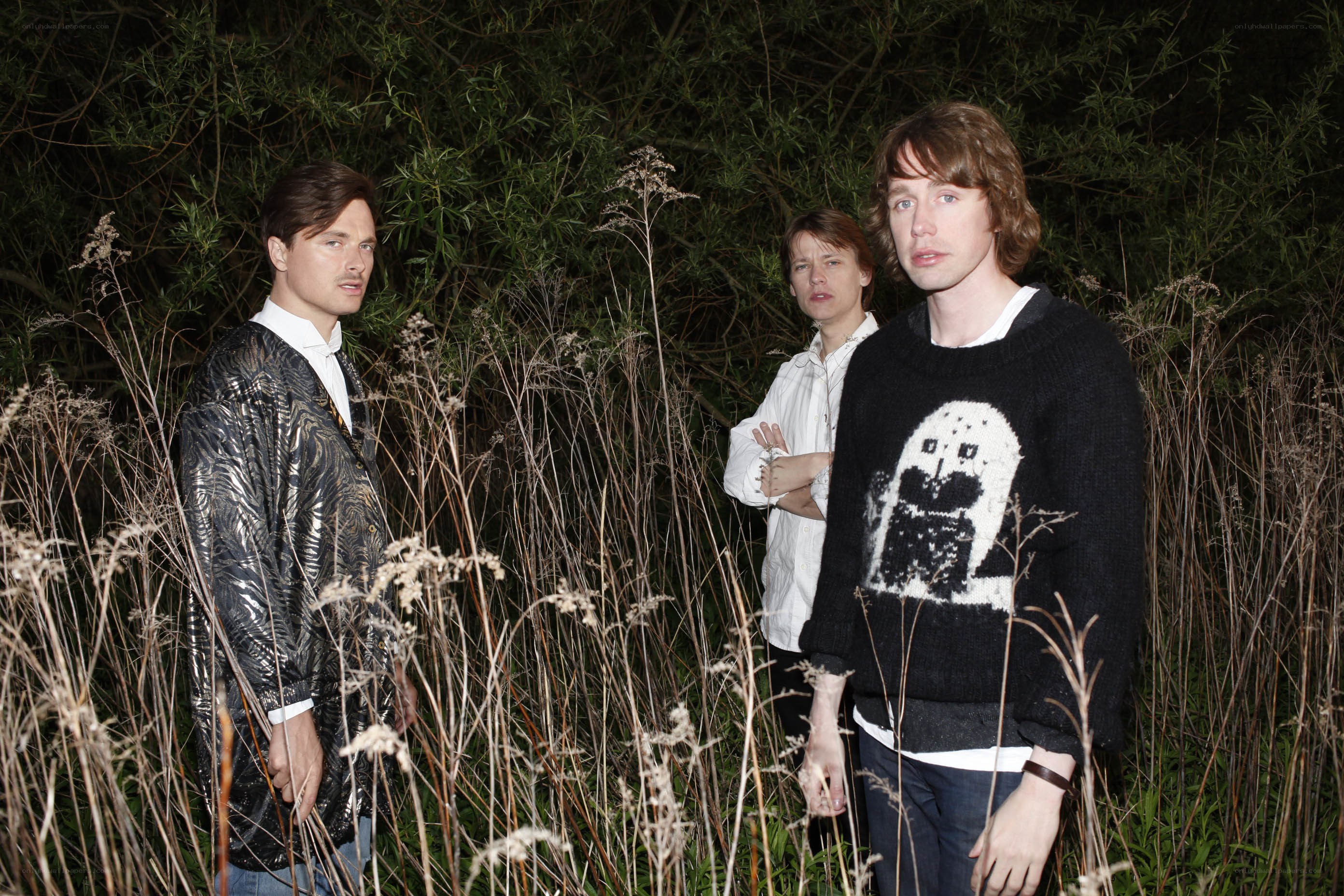 Three men in a field at night