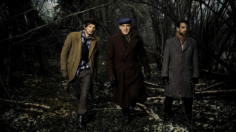 three men in coats in forest