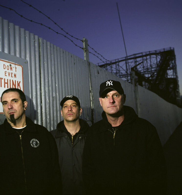 three men in front of a fence