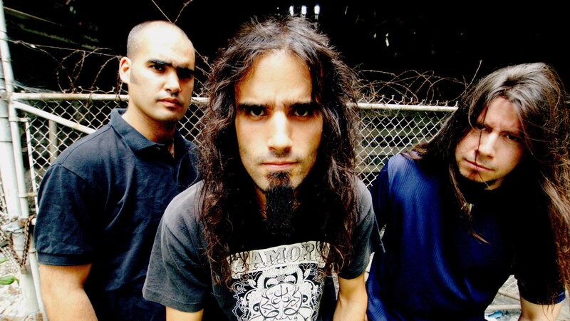 three men in front of chain-link fence