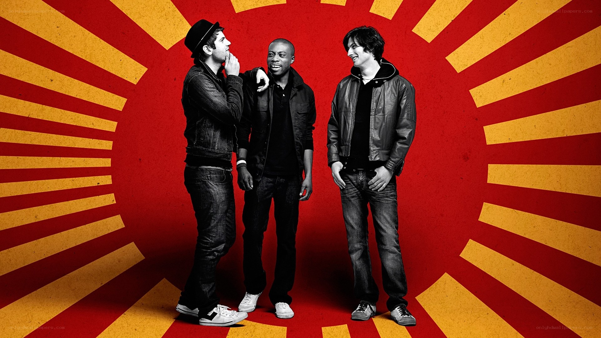 three men in front of sunburst background