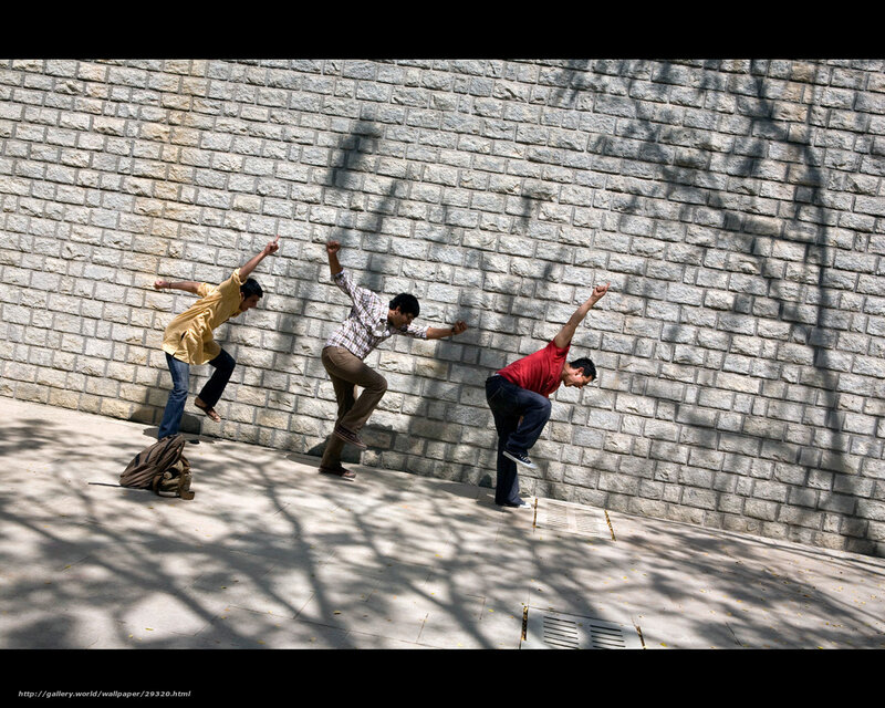 Three men in motion against a wall