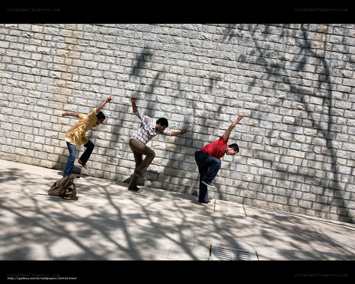 Three men in motion against a wall