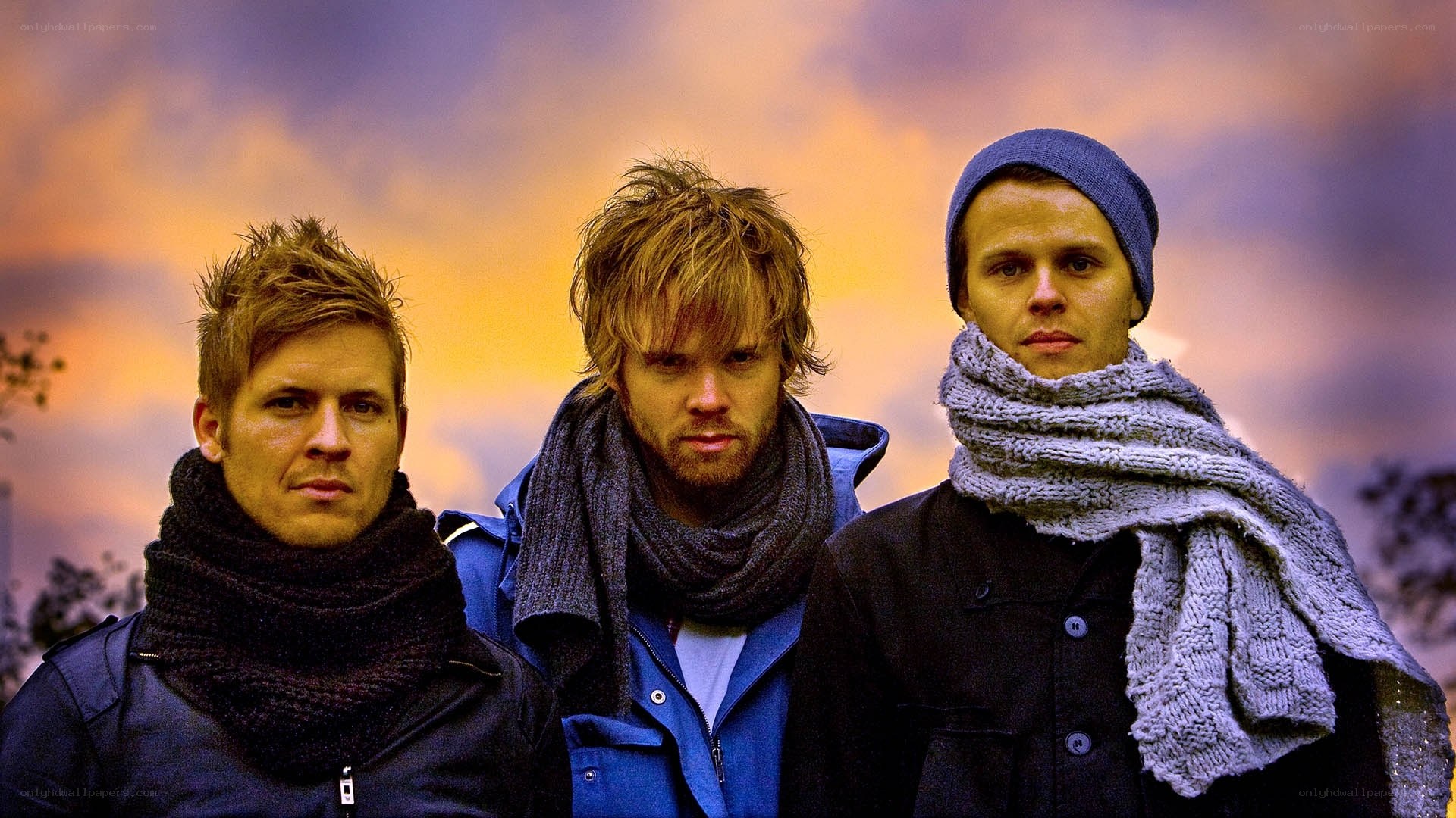 three men in scarves at sunset