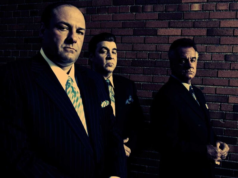 three men in suits against brick wall