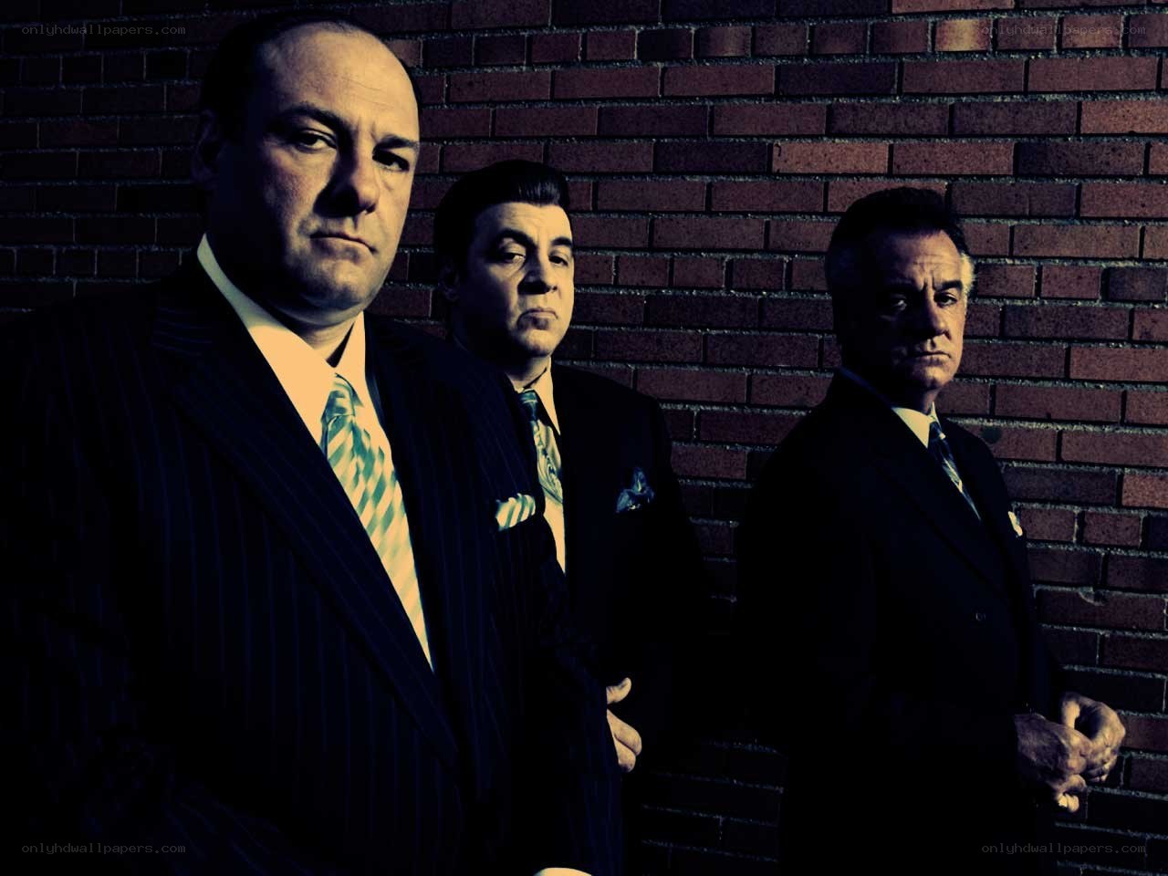 three men in suits against brick wall