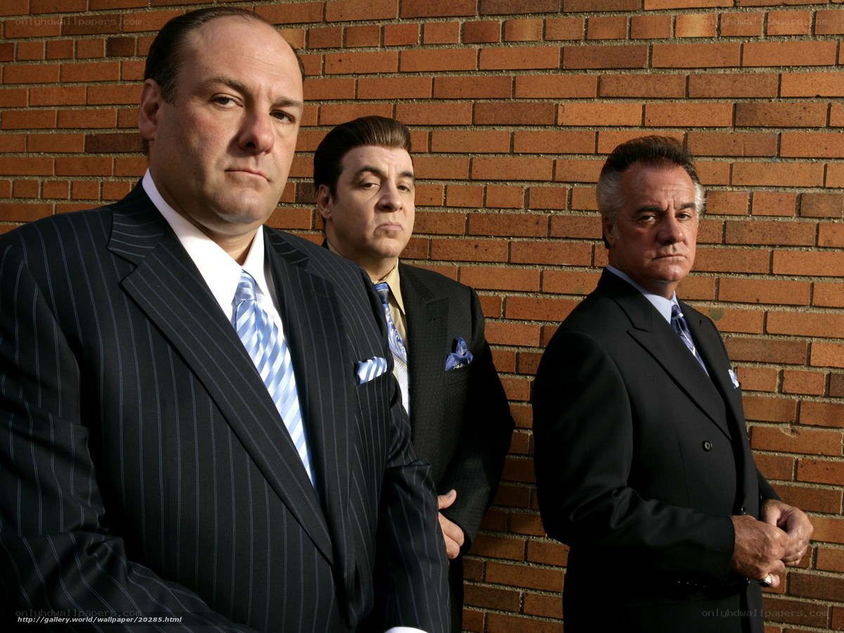 three men in suits against brick wall