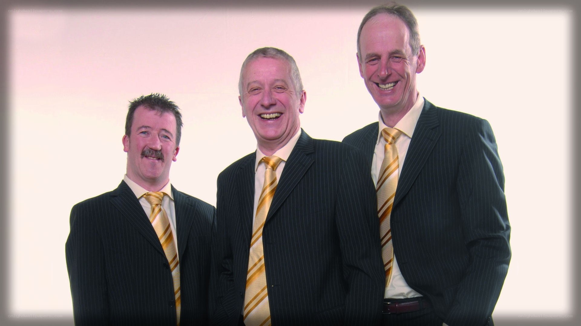Three men in suits smiling