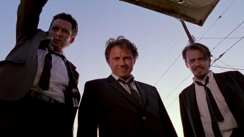 three men in suits under car