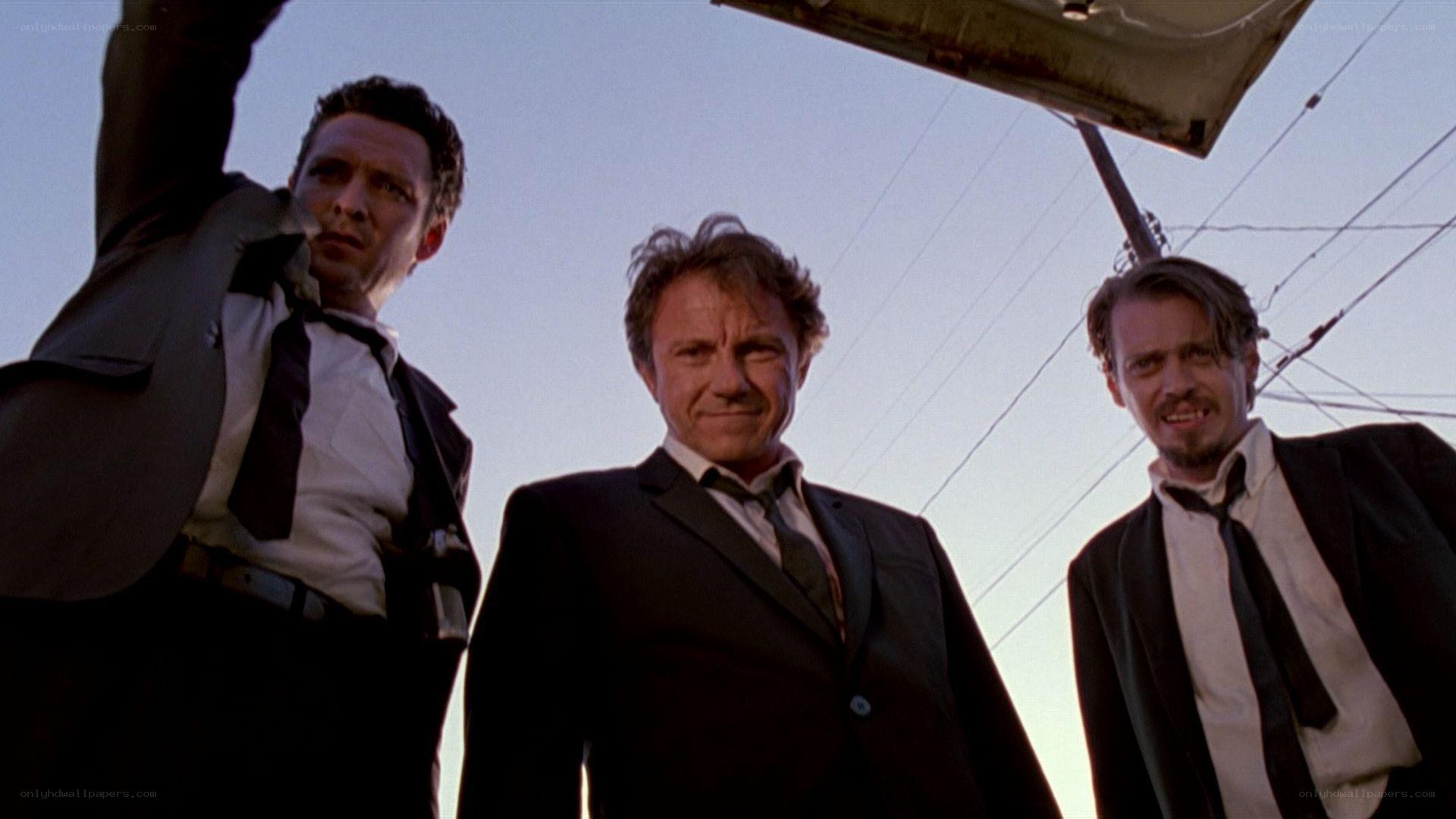three men in suits under car