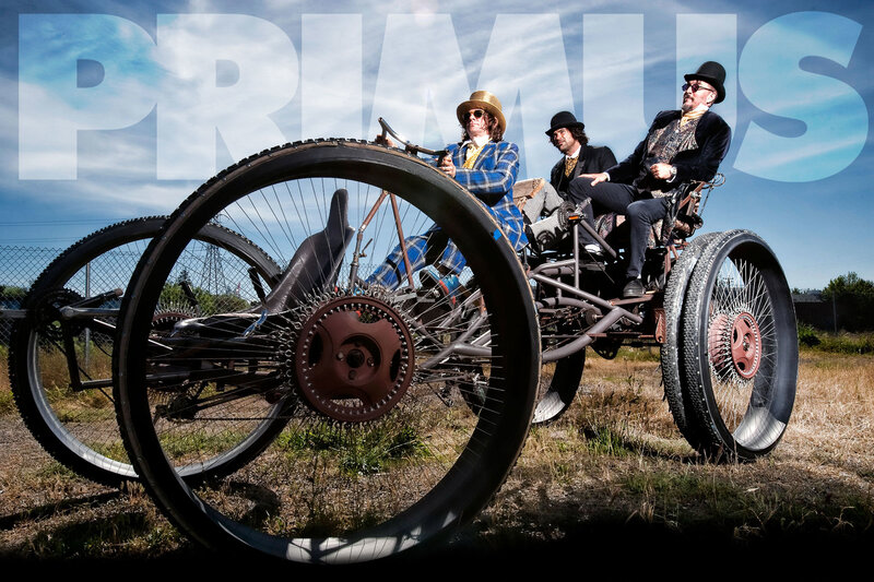 Three men in vintage attire on a custom vehicle