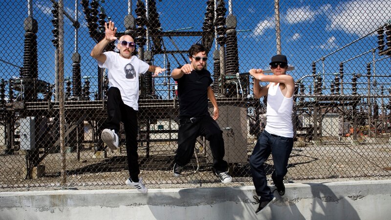 Three men jumping in front of power station