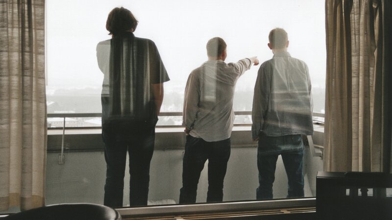 Three men looking out a window