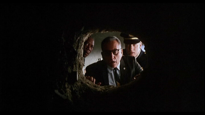 Three Men Looking Through Hole