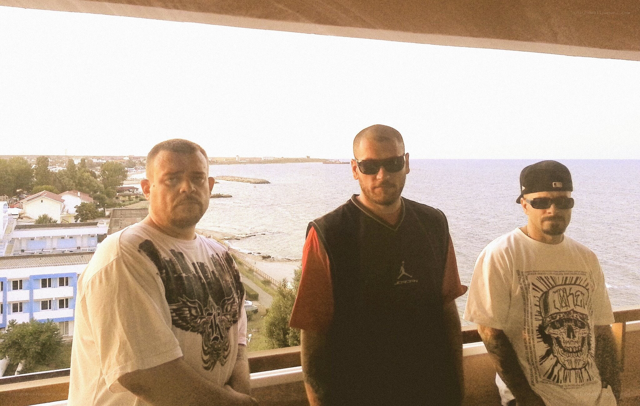 Three men on a balcony overlooking the sea