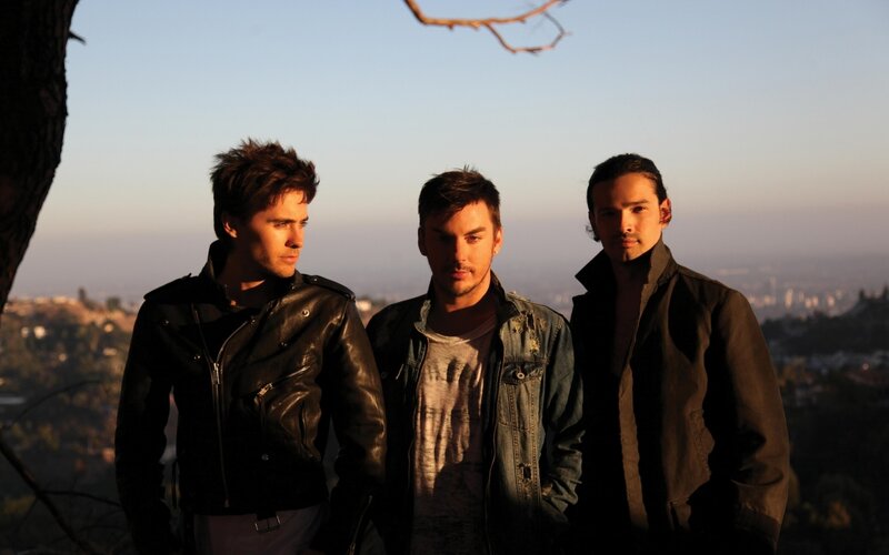 three men on a hill at sunset