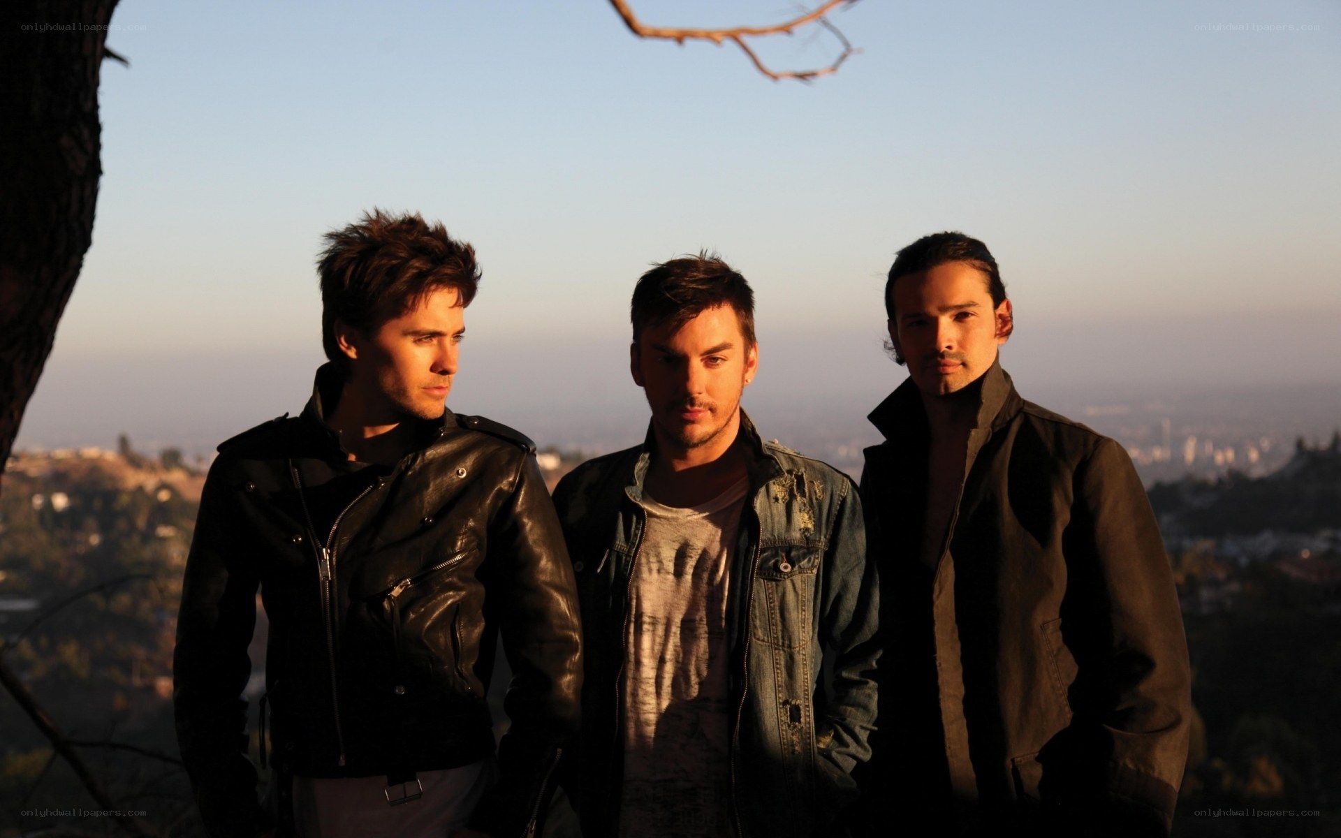 three men on a hill at sunset