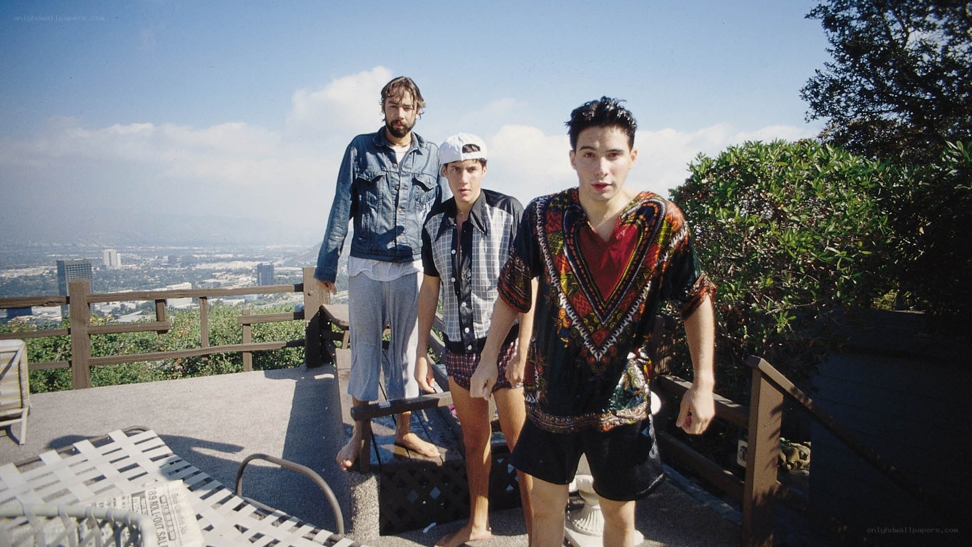 three men on a rooftop overlooking a city
