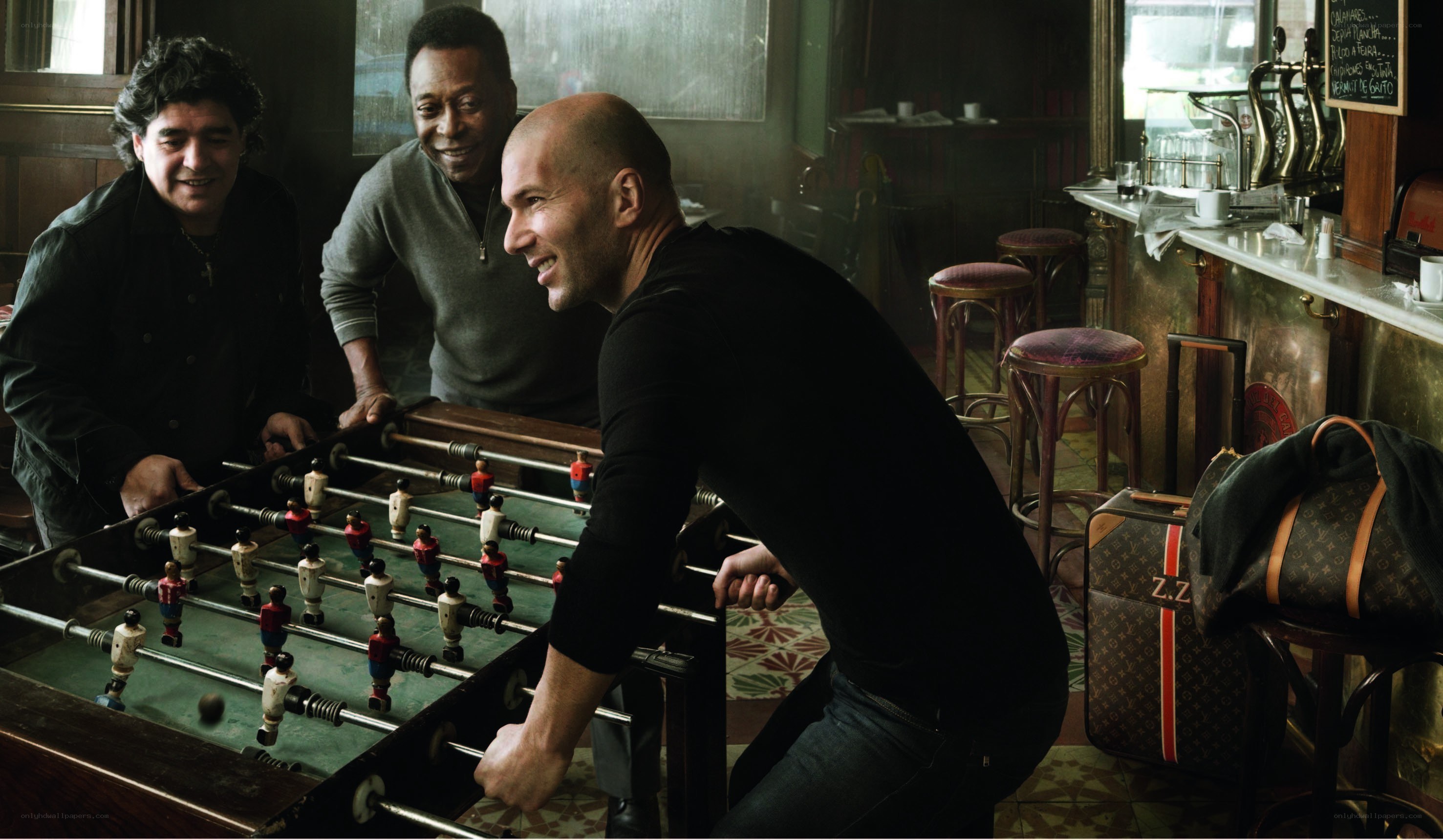 Three men playing foosball in a bar