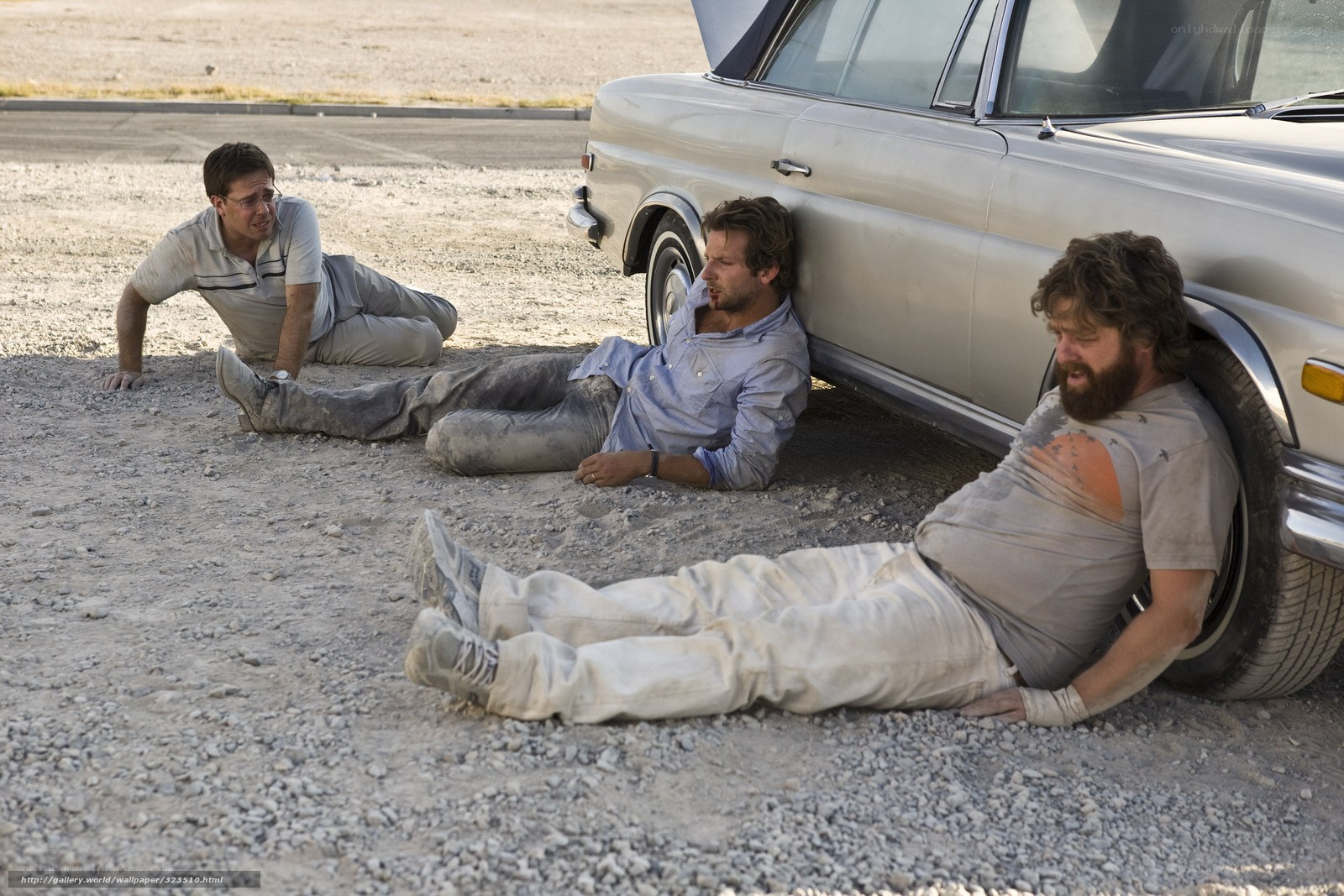 Three men resting by a car