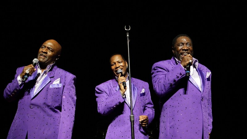 Three men singing in purple suits