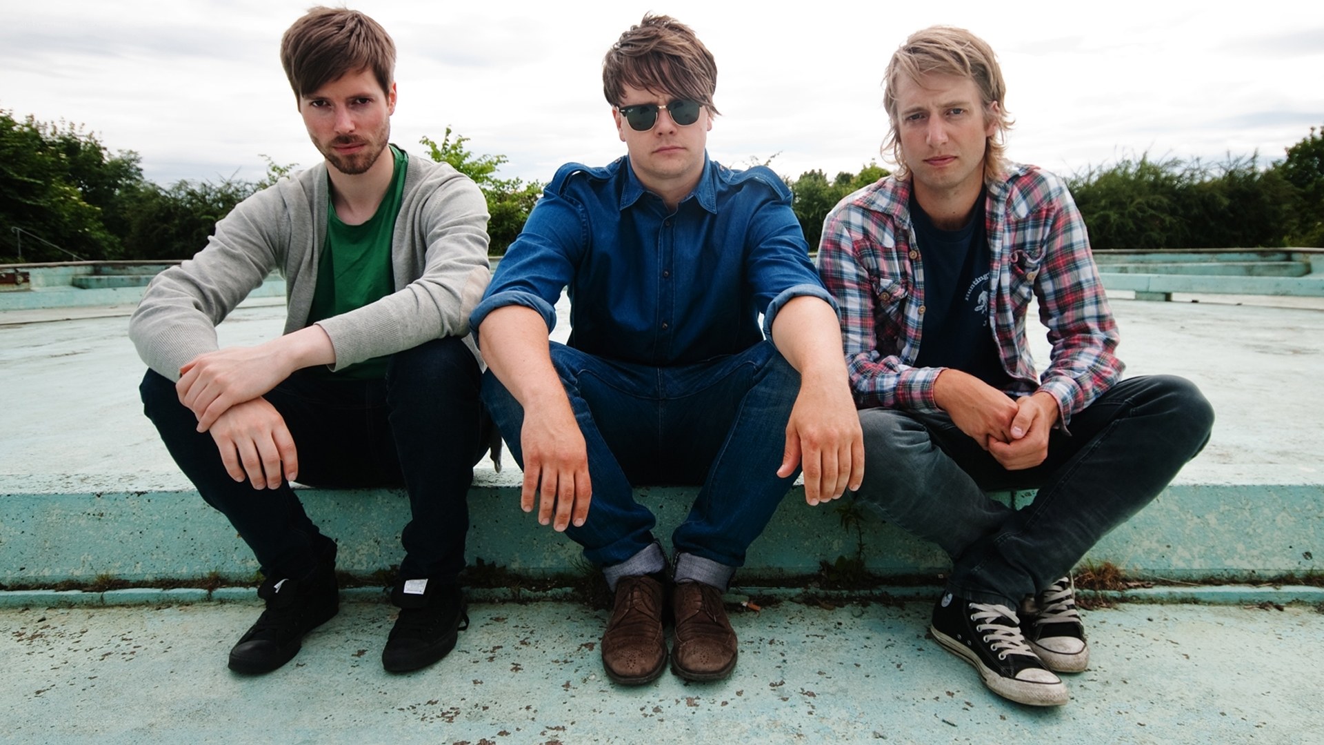 three men sitting on a ledge