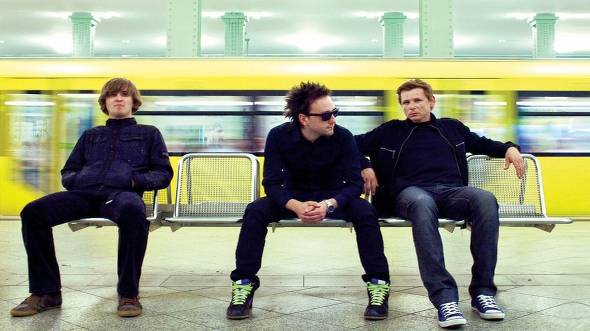 Three men sitting on a subway bench