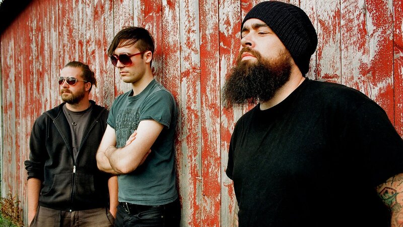 three men standing by a red wall
