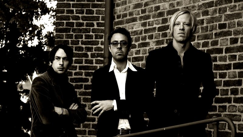 three men standing by brick wall