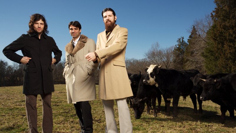 Three men with cows in a field