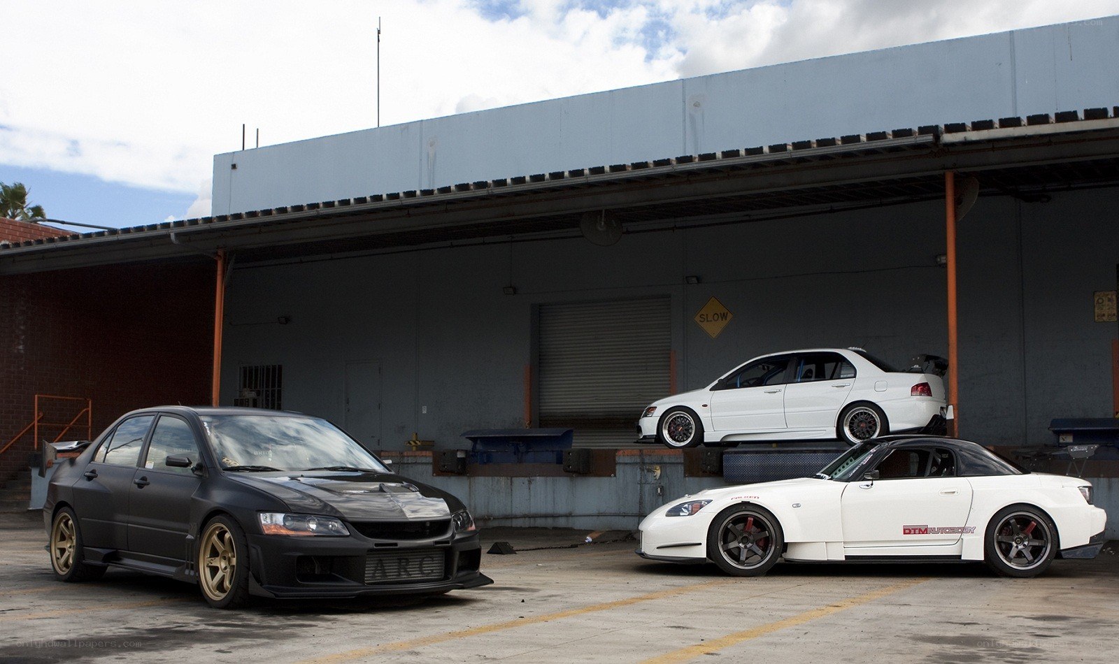 three modified cars in a lot