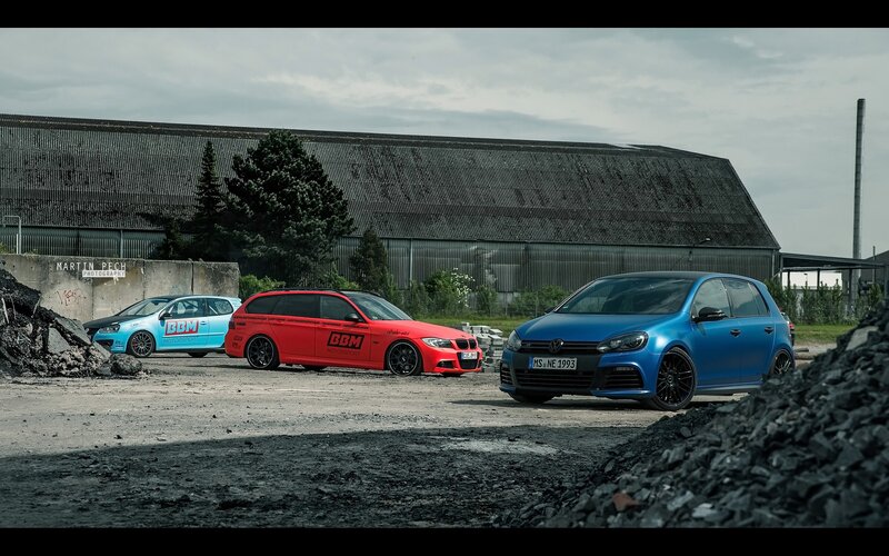 Three modified cars in an industrial lot