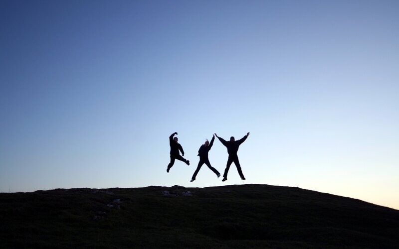 Three people jumping on a hill