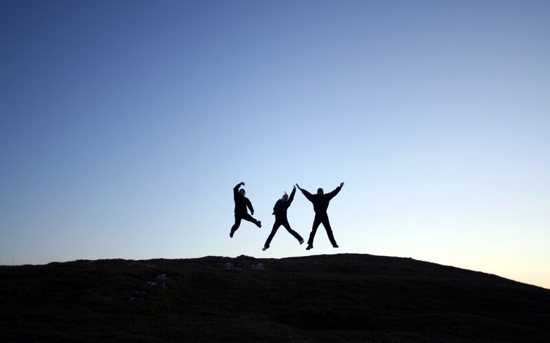 Three people jumping on a hill