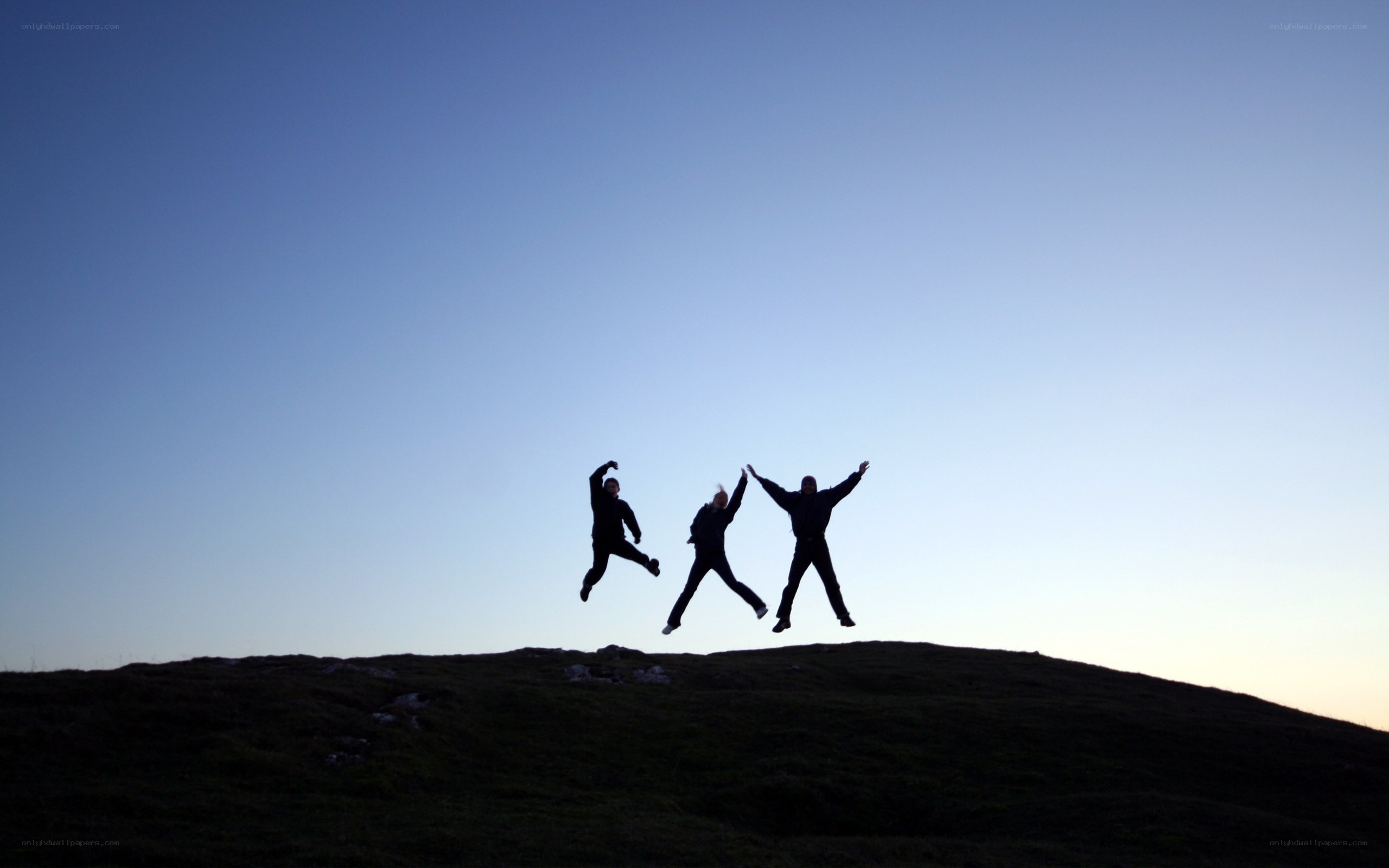 Three people jumping on a hill