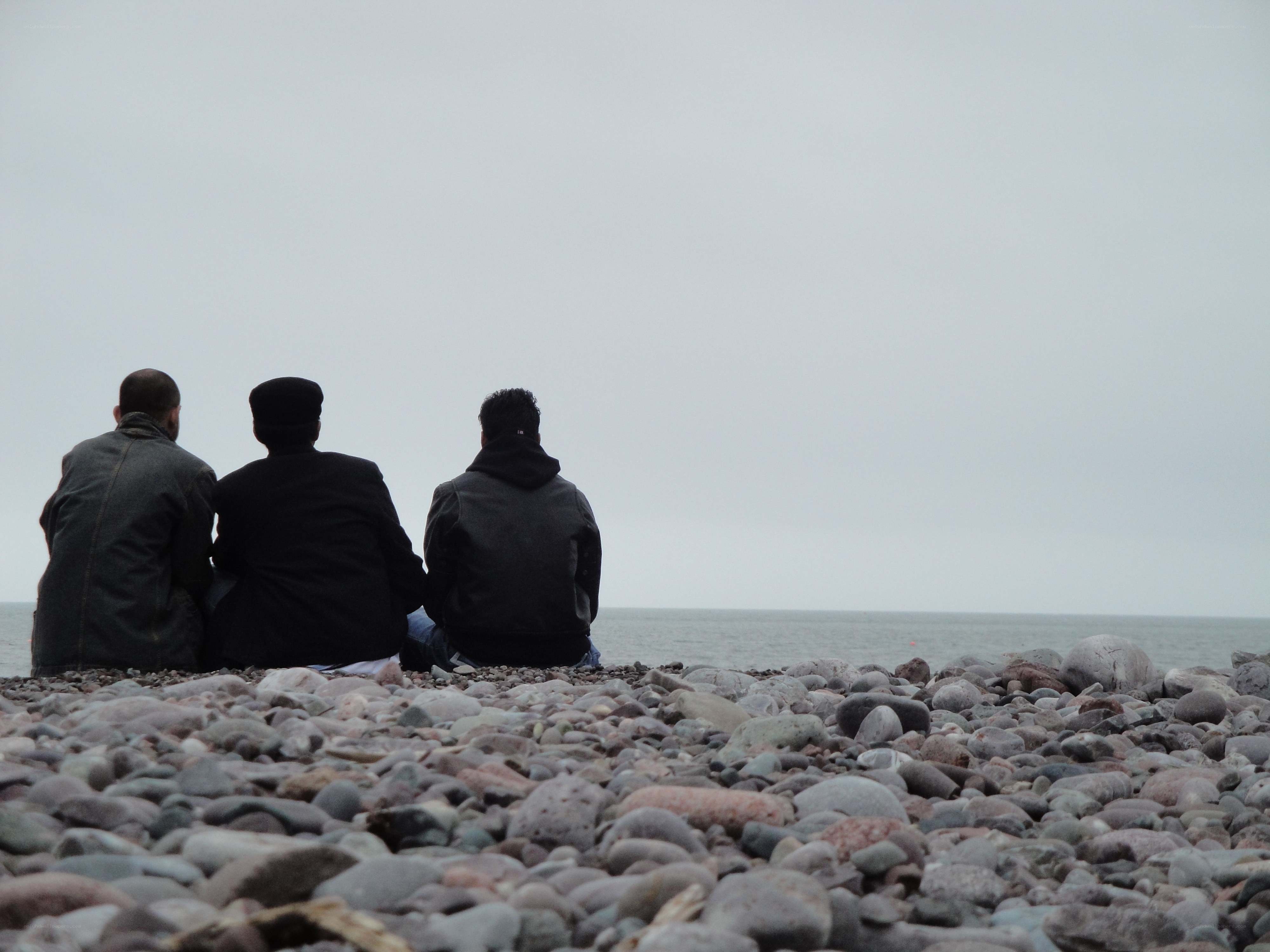 Three people on a pebble beach