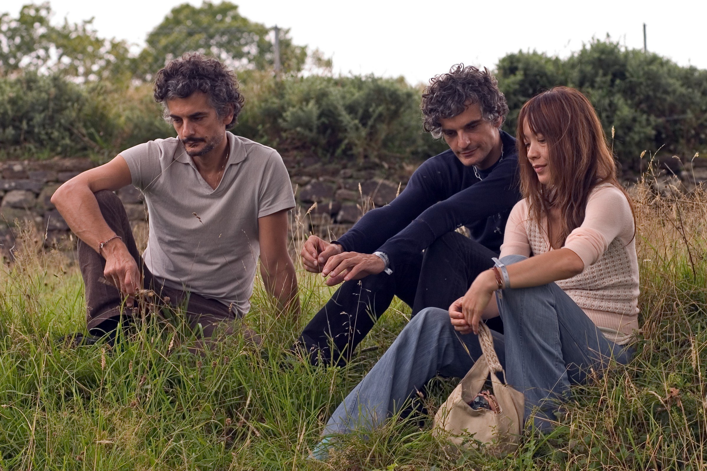Three people sitting in a field