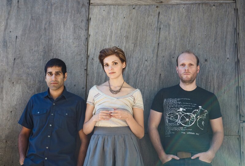 three people standing against a wooden wall