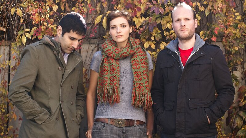 Three people standing in front of autumn leaves