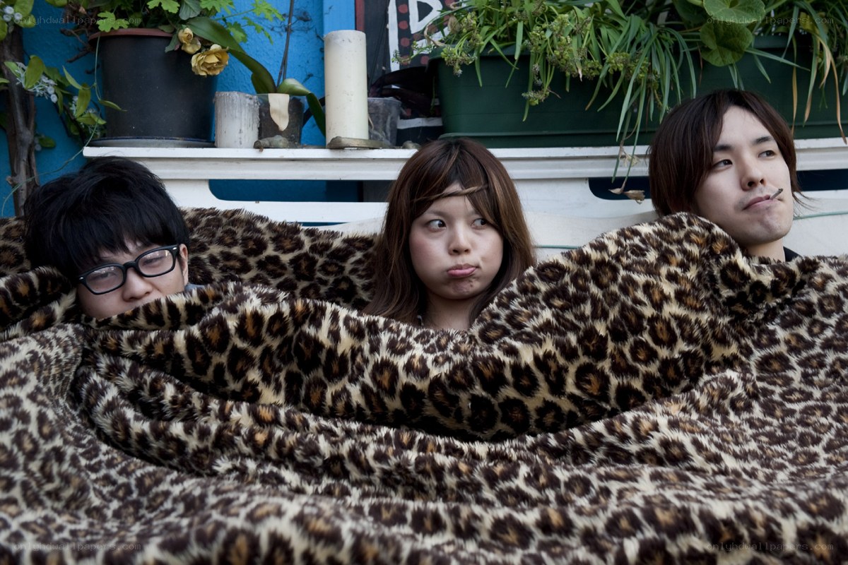 Three people under a leopard-print blanket