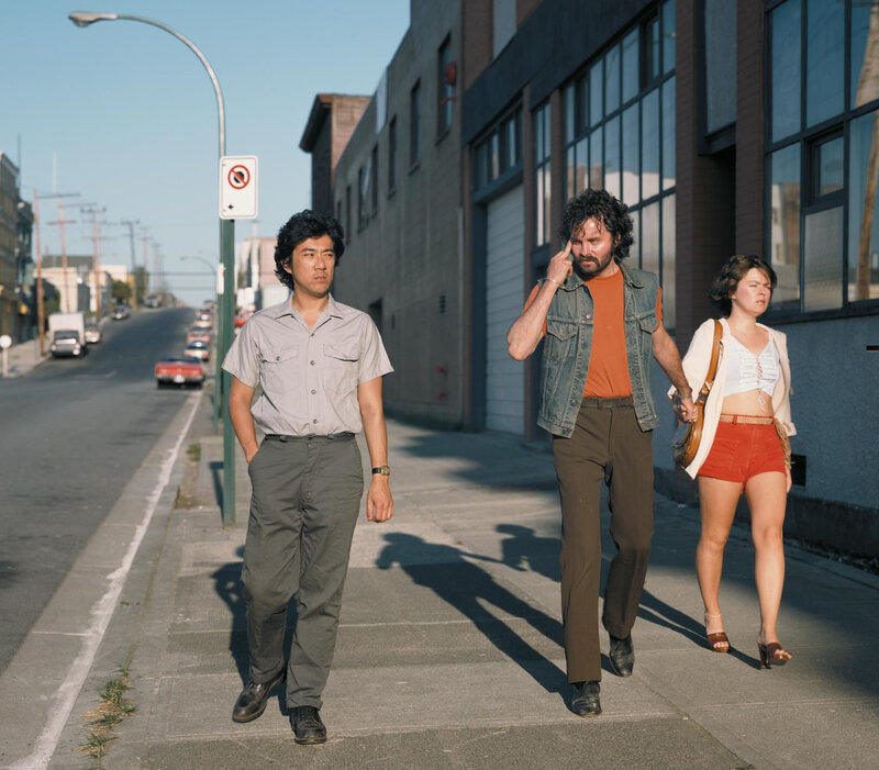 Three people walking on a sidewalk